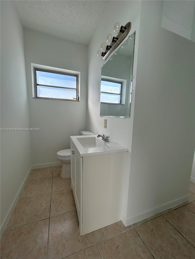 bathroom with vanity, toilet, tile patterned flooring, and a textured ceiling