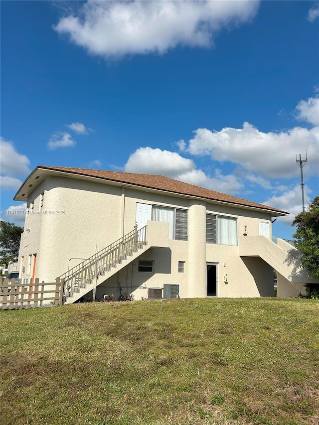 back of house with central AC and a lawn