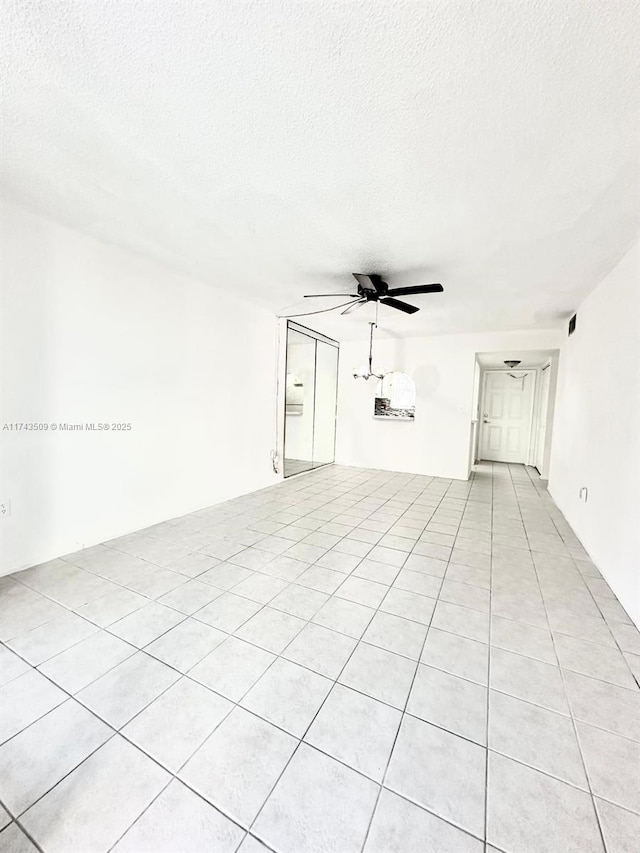 unfurnished living room featuring light tile patterned floors, a textured ceiling, and ceiling fan