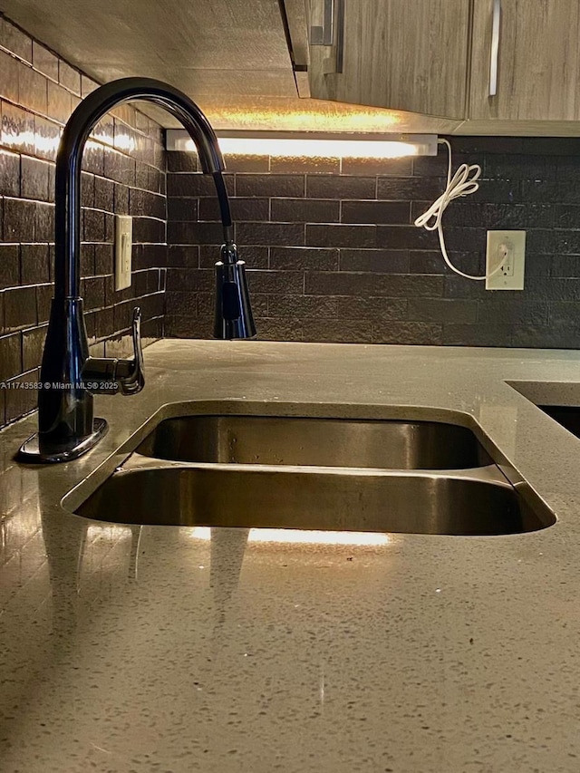 interior details featuring tasteful backsplash, light stone counters, and a sink