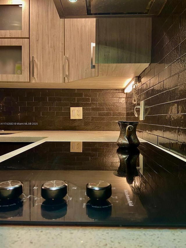 interior space with glass insert cabinets, light countertops, and light brown cabinets