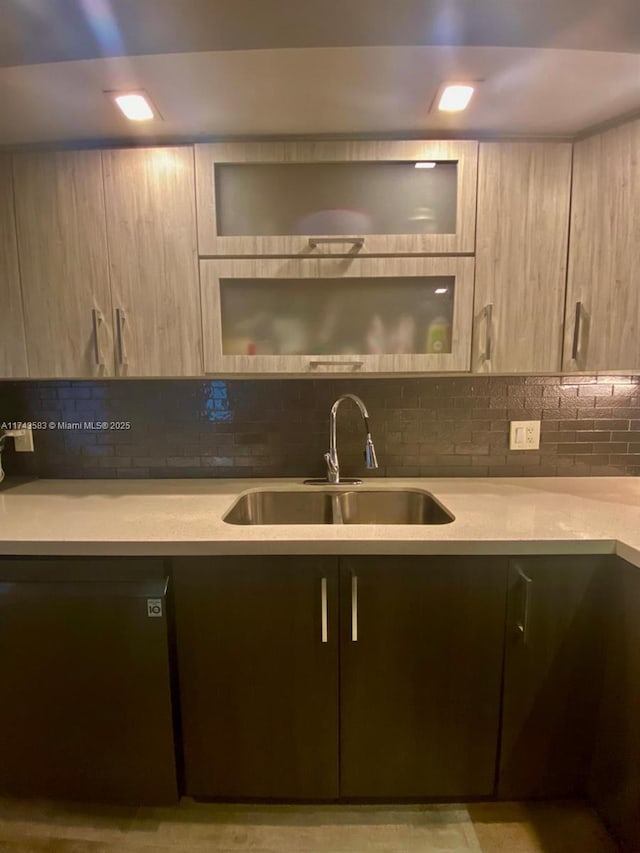 kitchen featuring light countertops, decorative backsplash, a sink, modern cabinets, and dishwashing machine