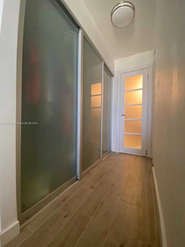 hall with baseboards and wood finished floors