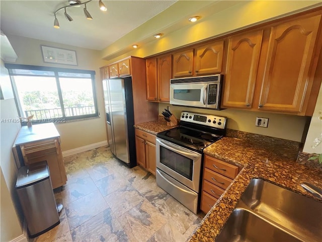 kitchen featuring sink, stainless steel appliances, and dark stone counters