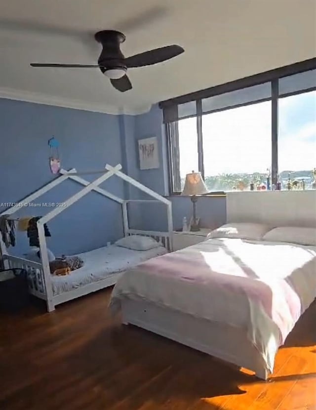 bedroom featuring hardwood / wood-style flooring, ceiling fan, and crown molding