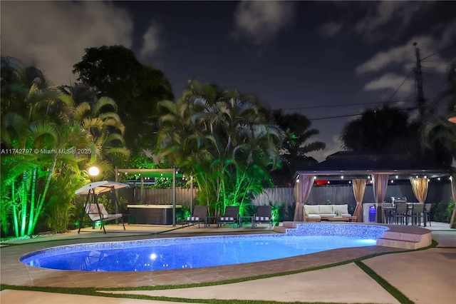 pool at night with an outdoor hangout area, a gazebo, and a patio area