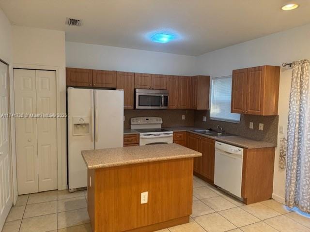 kitchen with a kitchen island, light tile patterned floors, white appliances, and decorative backsplash