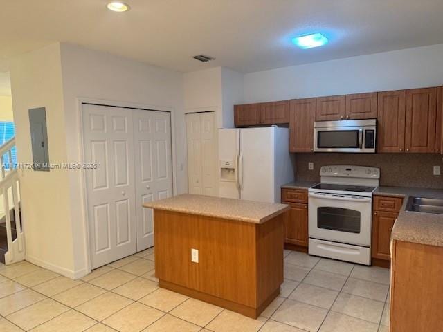 kitchen featuring a center island, light tile patterned floors, electric panel, white appliances, and decorative backsplash