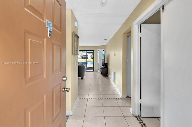 hallway with light tile patterned floors and a textured ceiling