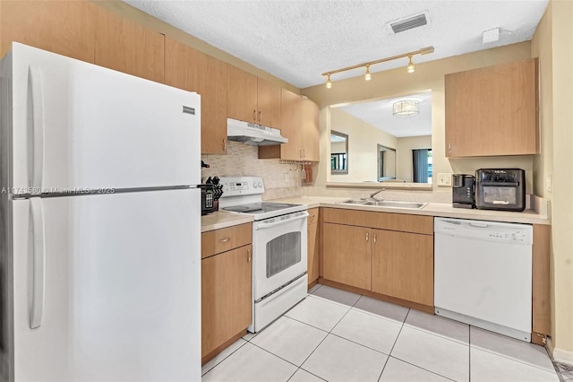 kitchen with sink, light tile patterned floors, white appliances, light brown cabinets, and a textured ceiling