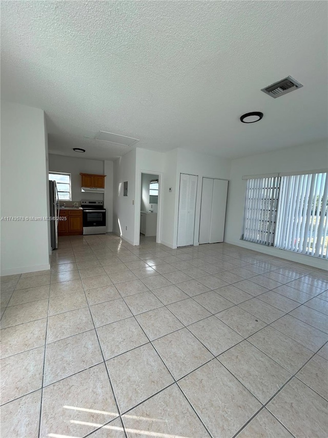 unfurnished living room featuring a textured ceiling and light tile patterned floors