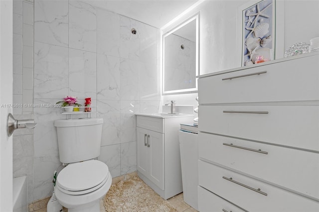 bathroom with vanity, toilet, a bathtub, and tile walls