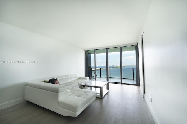 living room with expansive windows, a water view, and dark wood-type flooring