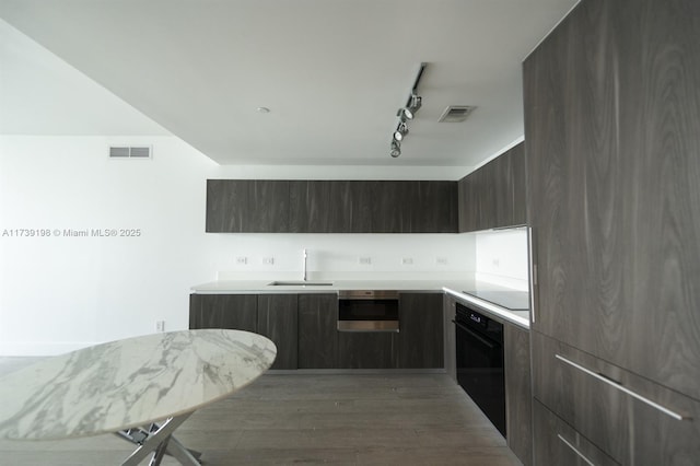 kitchen with sink, track lighting, dark hardwood / wood-style floors, and black appliances