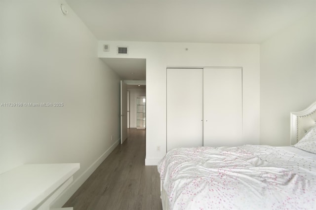 bedroom with dark hardwood / wood-style flooring and a closet