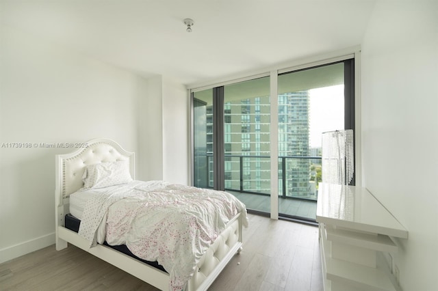 bedroom with expansive windows, hardwood / wood-style floors, and access to exterior