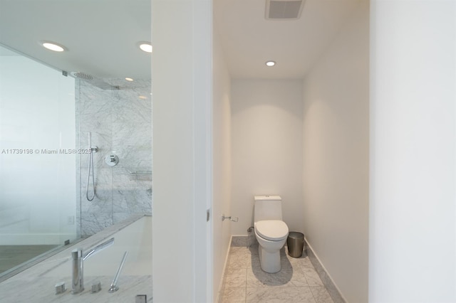 bathroom featuring a tile shower and toilet