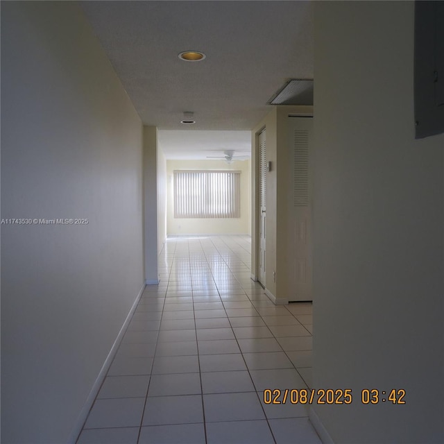 corridor with light tile patterned flooring and electric panel