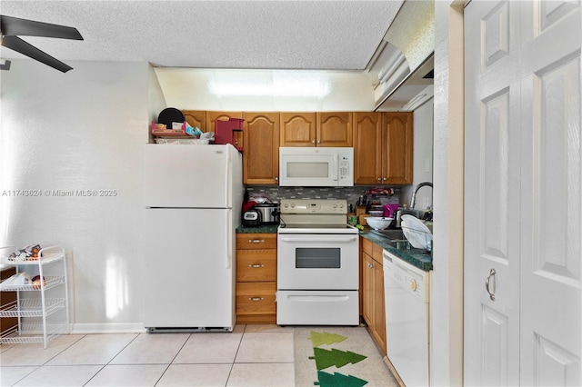 kitchen featuring white appliances, light tile patterned floors, dark countertops, brown cabinets, and a textured ceiling