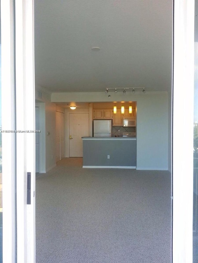 unfurnished living room featuring light carpet and track lighting