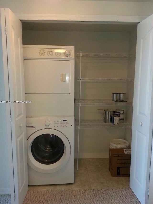 laundry room featuring light tile patterned floors and stacked washer / dryer