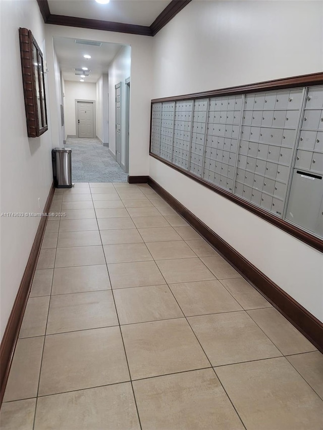 hall featuring mail area, baseboards, crown molding, and tile patterned flooring