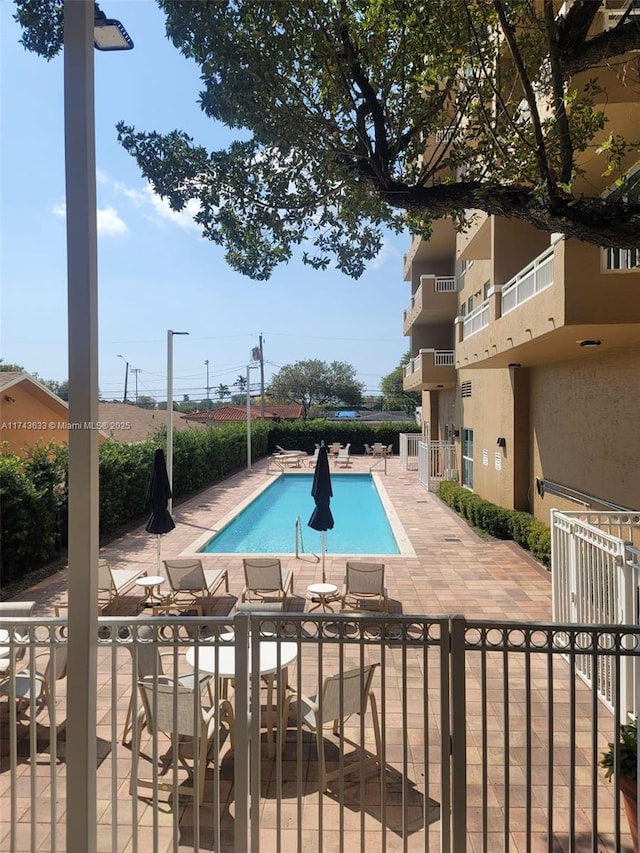 community pool with a patio and fence