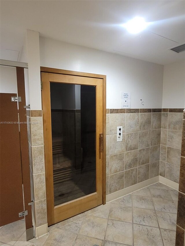 bathroom with visible vents, tile walls, and a wainscoted wall