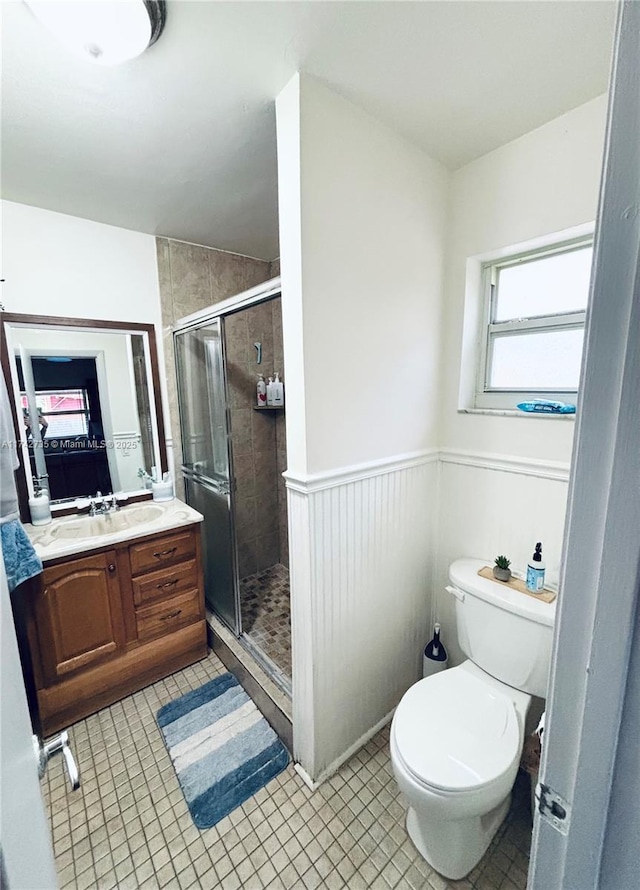 bathroom with vanity, toilet, tile patterned flooring, and a shower with door