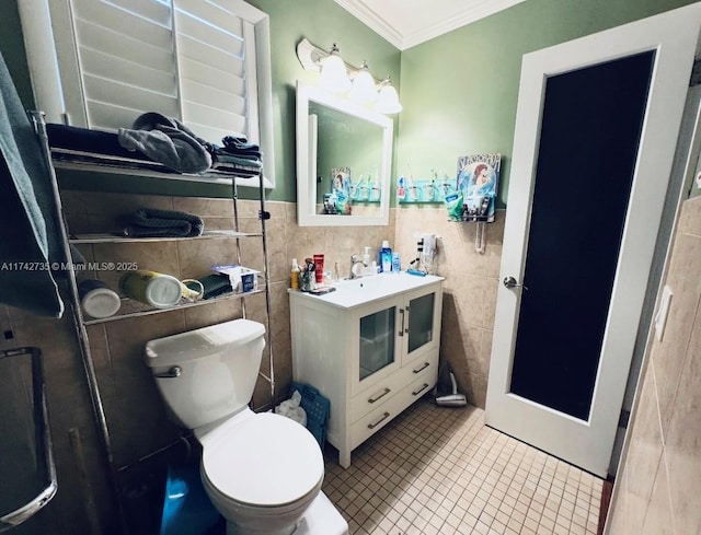 bathroom featuring tile patterned floors, toilet, tile walls, ornamental molding, and vanity