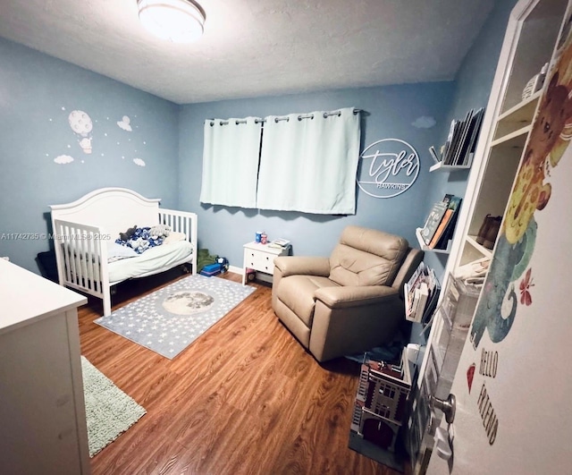 bedroom featuring hardwood / wood-style flooring and a crib