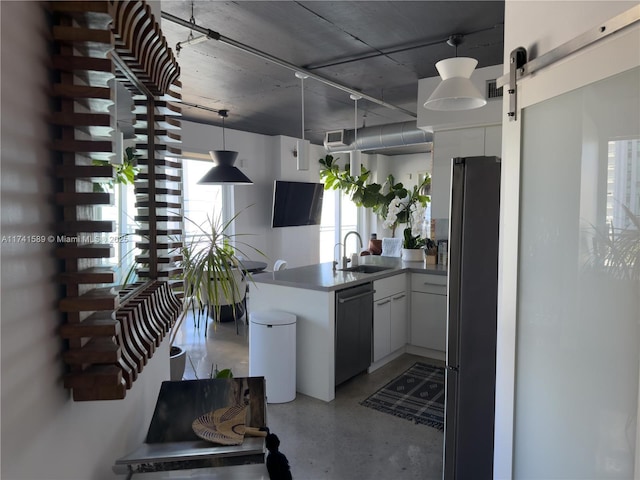 kitchen featuring sink, kitchen peninsula, stainless steel appliances, a barn door, and white cabinets