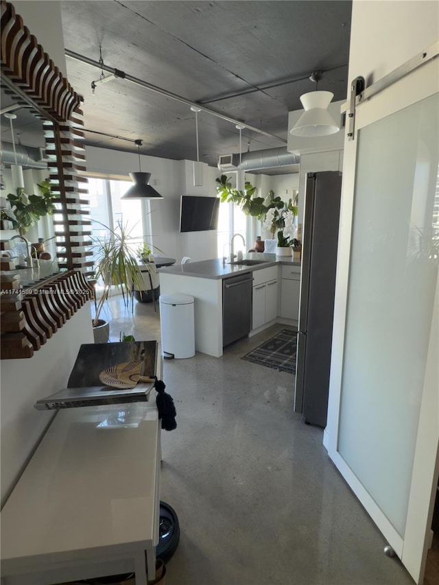 kitchen with sink, white cabinetry, stainless steel appliances, a wealth of natural light, and a barn door