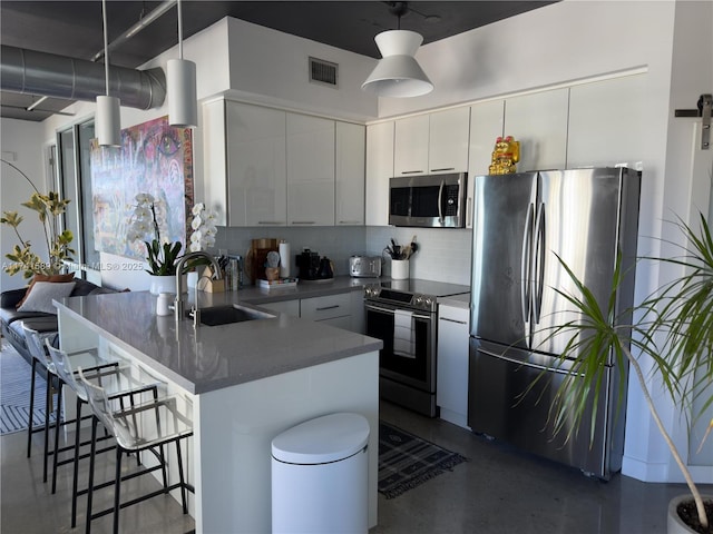 kitchen with sink, a kitchen bar, hanging light fixtures, and appliances with stainless steel finishes