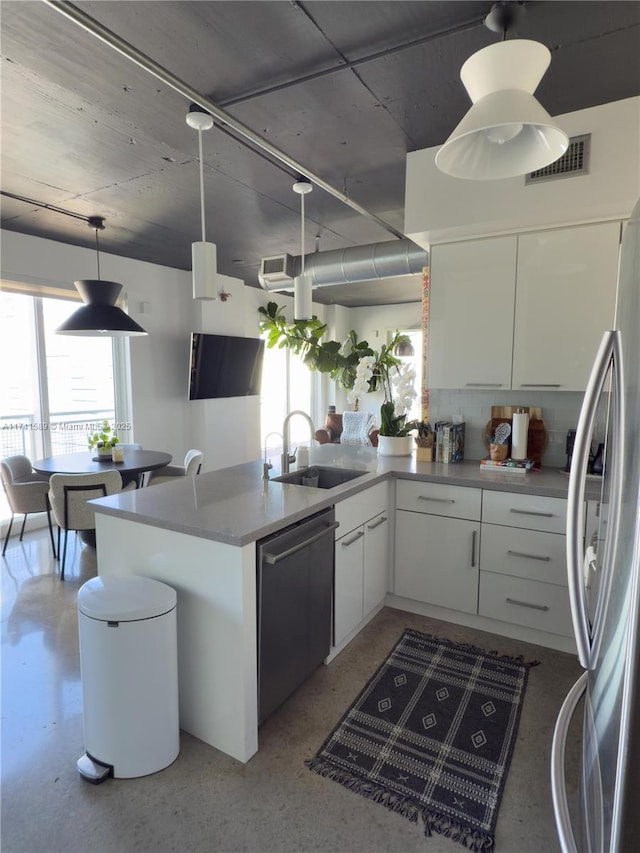 kitchen featuring sink, appliances with stainless steel finishes, white cabinets, decorative light fixtures, and kitchen peninsula