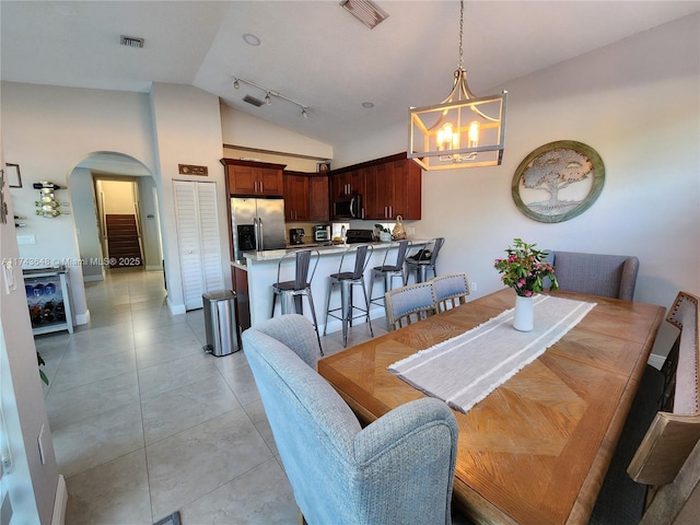 tiled dining area with a notable chandelier, vaulted ceiling, and track lighting