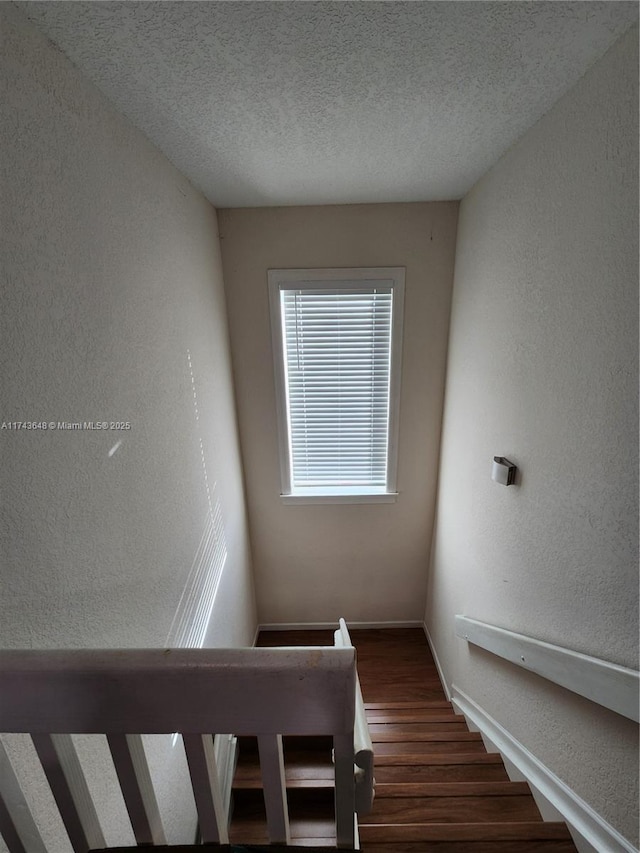 staircase featuring wood-type flooring and a textured ceiling