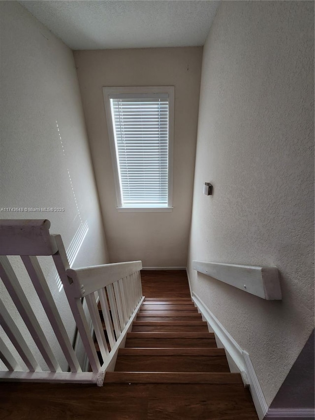 staircase with hardwood / wood-style floors and a textured ceiling