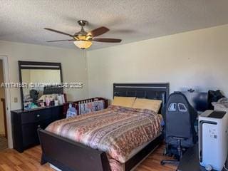 bedroom featuring wood-type flooring, ceiling fan, and a textured ceiling