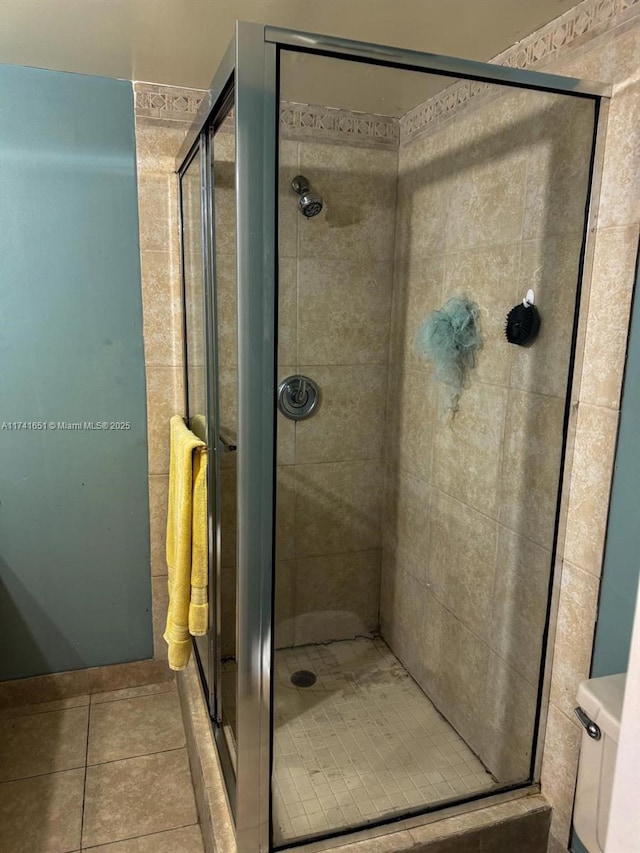 bathroom with toilet, a shower with shower door, and tile patterned flooring