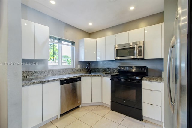 1431 NE 156th Ter, North Miami Beach, FL 33162 - kitchen with appliances with stainless steel finishes, white cabinets, light stone counters, recessed lighting, and light tile patterned flooring