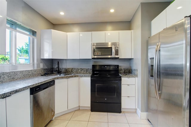 1431 NE 156th Ter, North Miami Beach, FL 33162 - kitchen featuring stainless steel appliances, white cabinetry, light stone countertops, light tile patterned floors, and recessed lighting