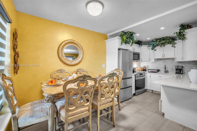 kitchen featuring sink, white cabinetry, stainless steel appliances, a textured ceiling, and decorative backsplash