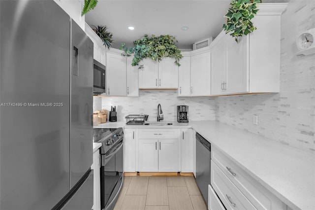 kitchen with sink, light tile patterned floors, stainless steel appliances, decorative backsplash, and white cabinets