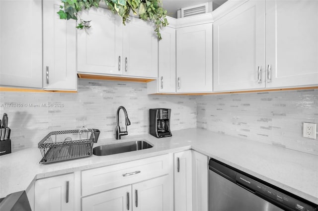 kitchen featuring dishwasher, sink, white cabinets, decorative backsplash, and light stone countertops