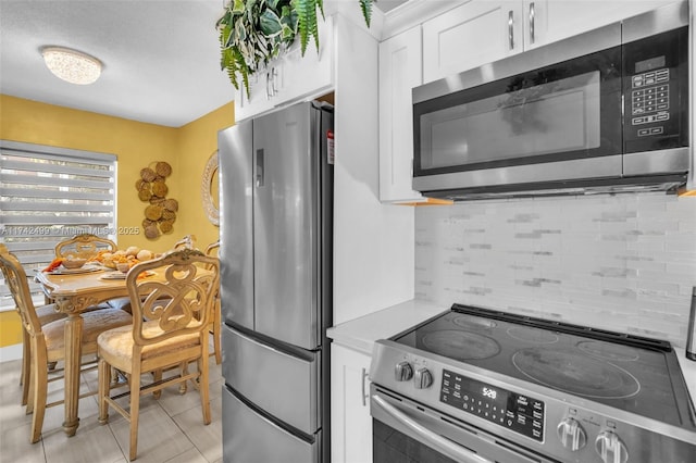 kitchen with decorative backsplash, stainless steel appliances, white cabinets, and light tile patterned flooring