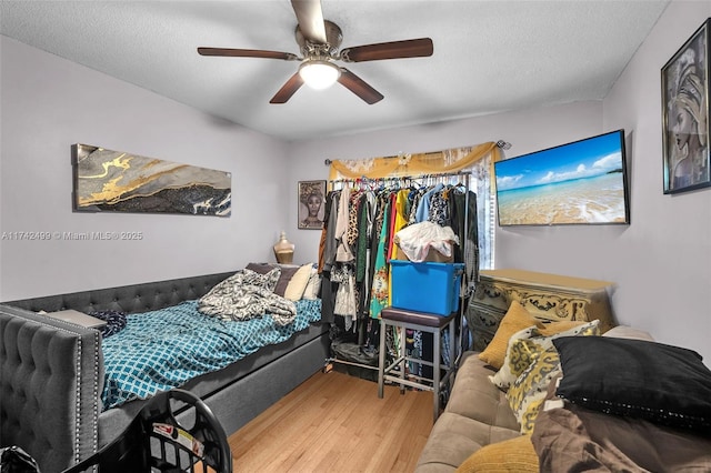 bedroom with ceiling fan, hardwood / wood-style floors, and a textured ceiling