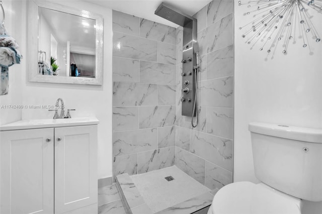 bathroom with a tile shower, vanity, and toilet