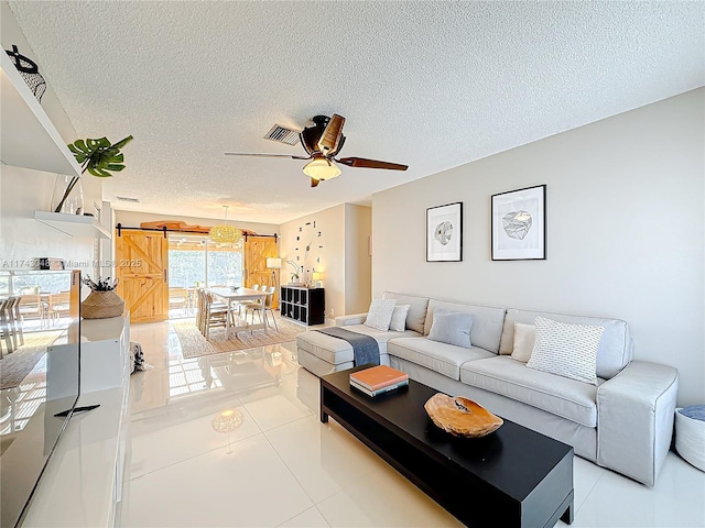 living room with visible vents, ceiling fan, tile patterned flooring, and a textured ceiling