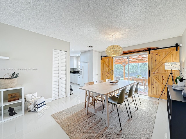 dining area featuring a textured ceiling, light tile patterned floors, visible vents, and a barn door